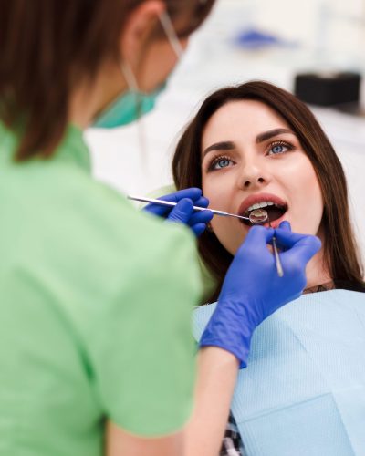 Dentist does an oral examination. Pretty patient woman came to the dentist’s appointment 2BB4HAW Dentist does an oral examination. Pretty patient woman came to the dentist's appointment